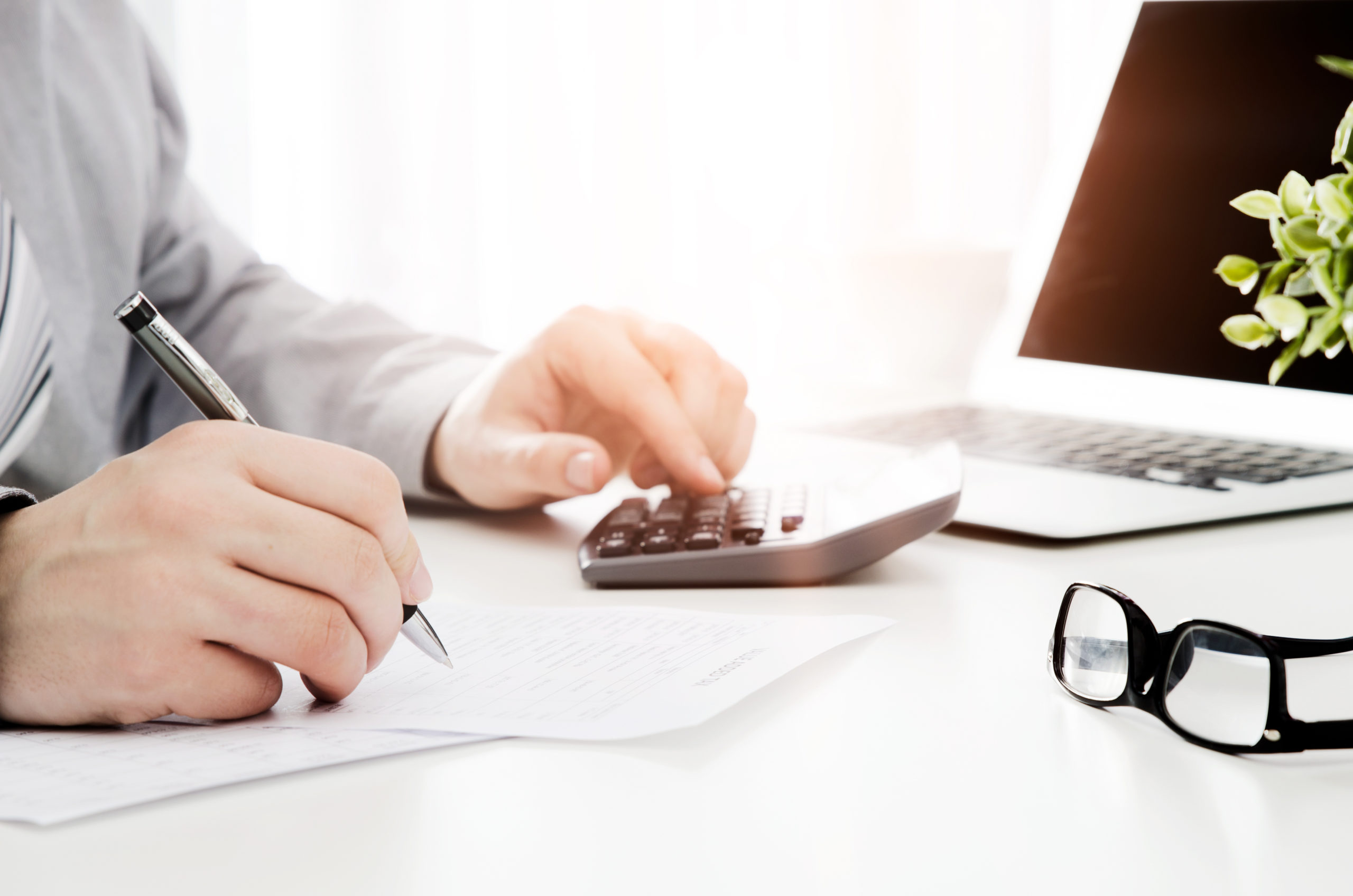 Mann am Arbeitsplatz mit Taschenrechner