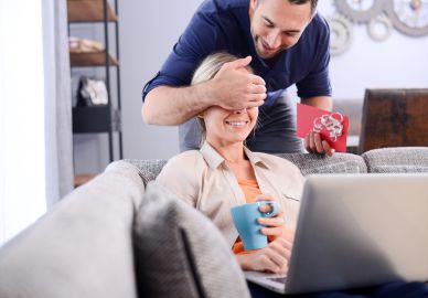 Mann &uuml;berrascht Frau mit Geschenkgutschein